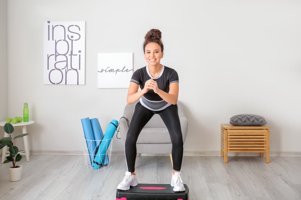 Active young woman stepped with both legs on top of the stepper