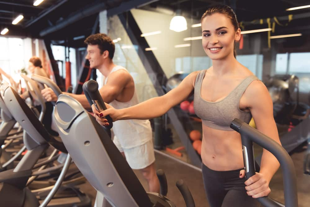 A group of fit people working out on elliptical machines in a gym