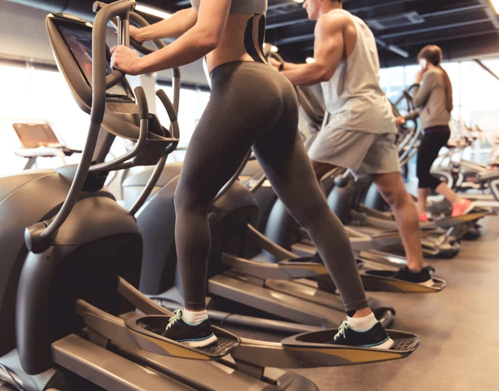 Legs of the people exercising on elliptical machines look to be fit, strong and healthy