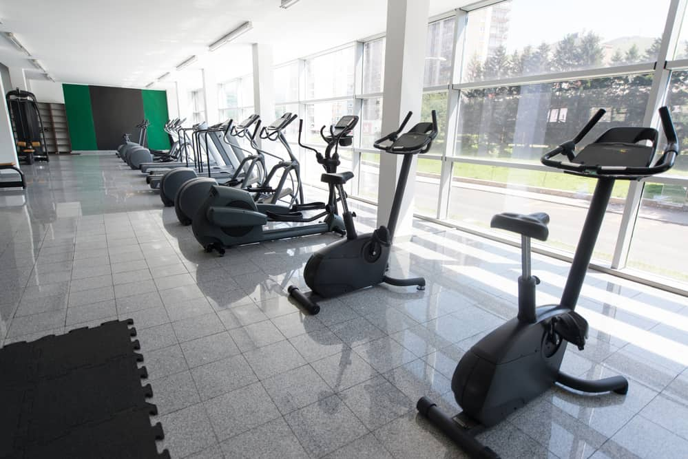 A row of exercise bikes and elliptical trainers in a gym