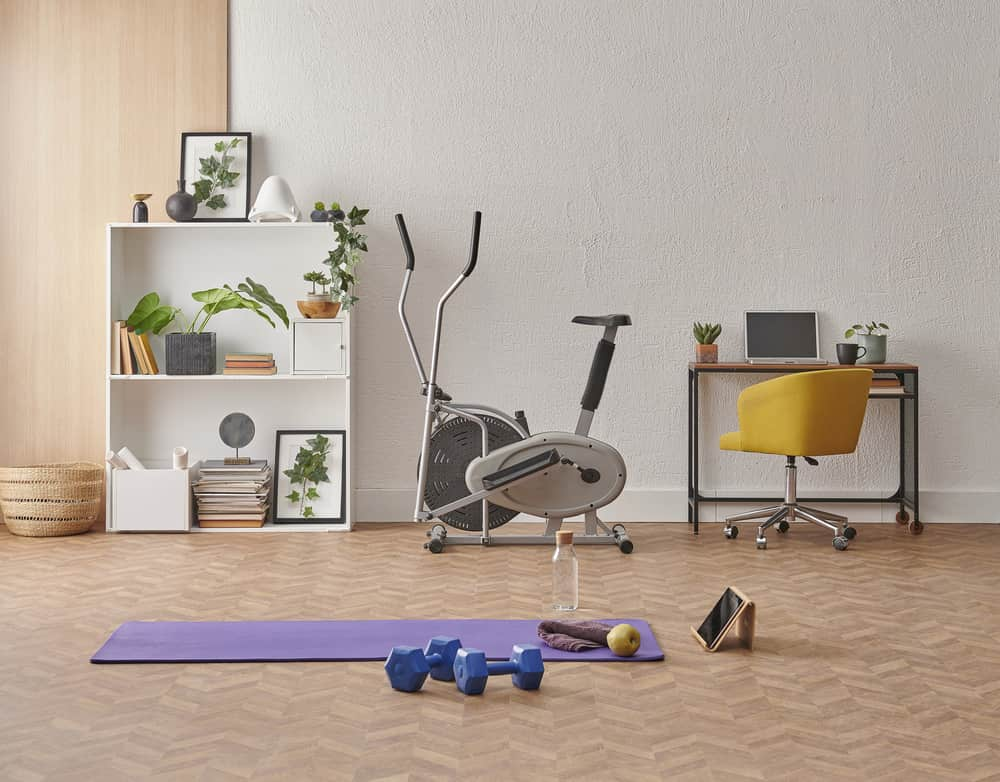 Some exercise accessories on the floor of a living along with an elliptical cross trainer