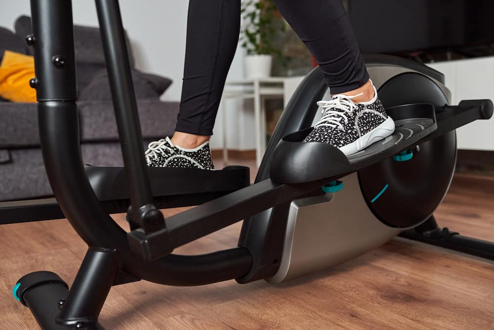 The feet of a person working out on an elliptical cross trainer machine