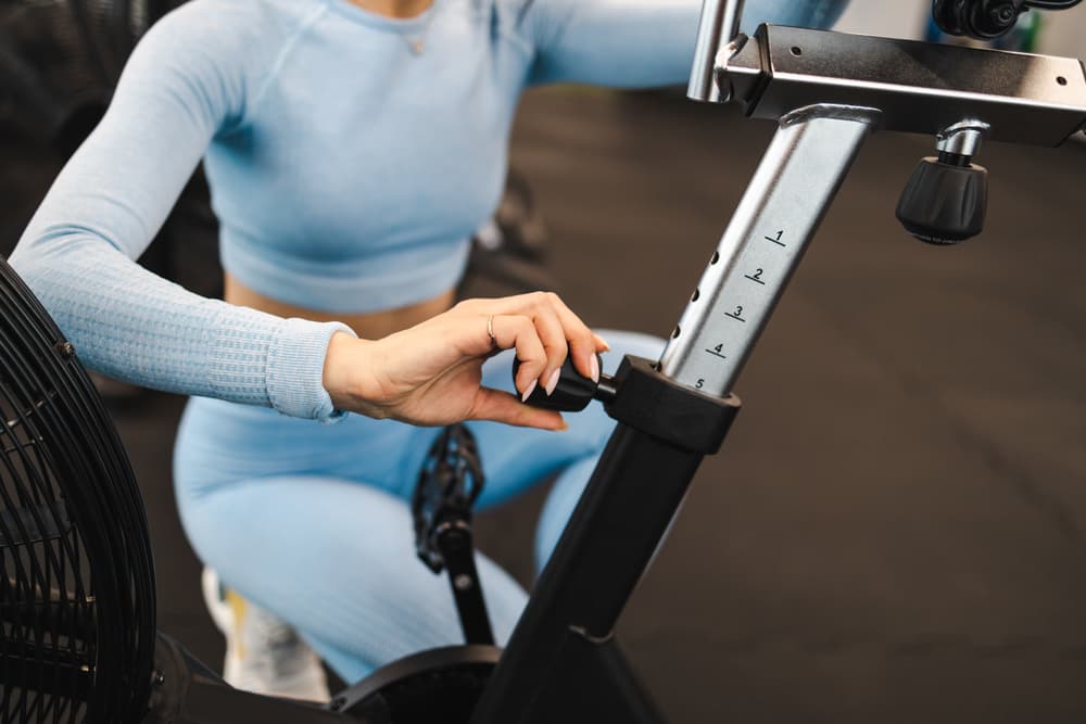 Woman Adjusting the Saddle Height to Avoid Exercise Bike Mistakes